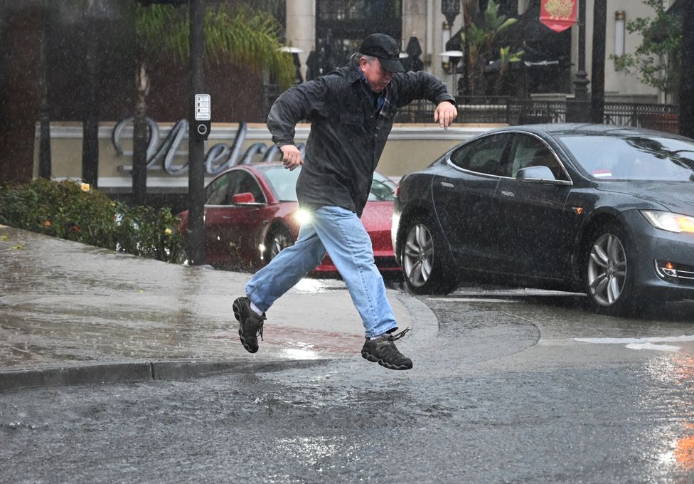 Man jumps over, or into, a large puddle in Glendale