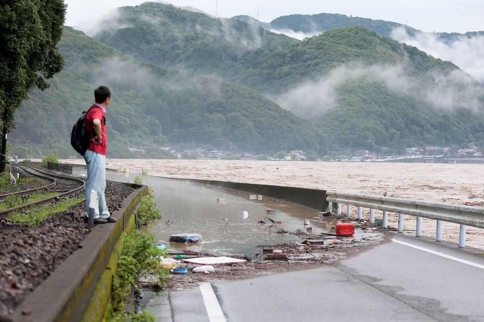 A man looks at the overflowing Kuma river in Yatsushiro, Kumamoto prefecture, 4 July