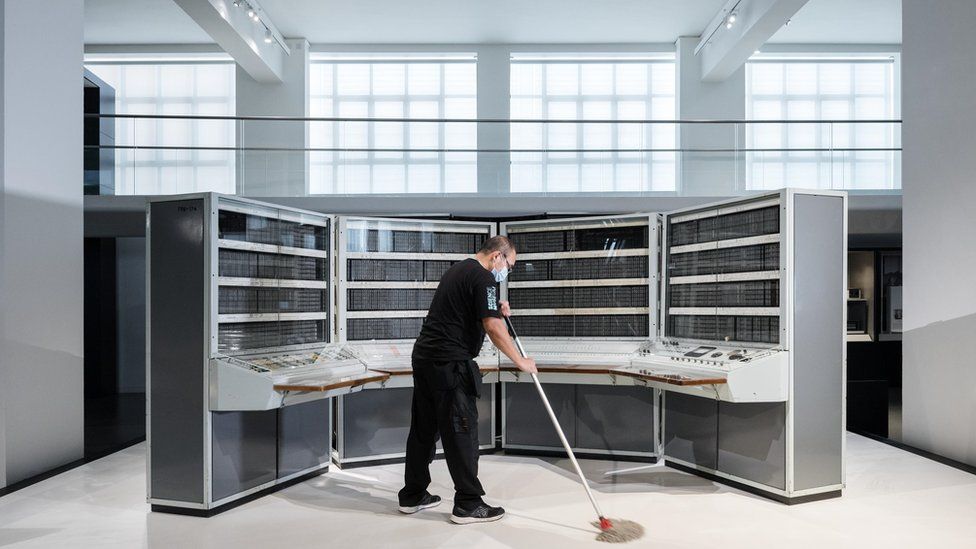 A conservator cleans a supercomputer during lockdown at the Science Museum