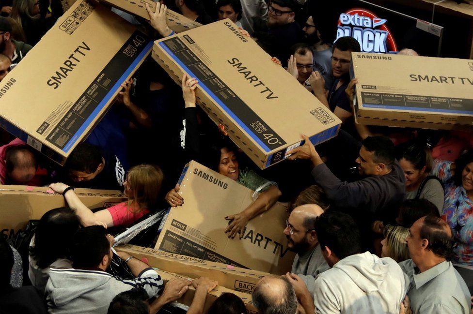 Shoppers reach out for television sets as they compete to purchase retail items on Black Friday.