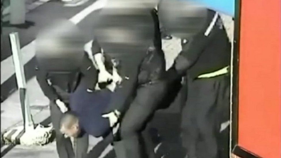 Leon Briggs being carried by police officers to police van