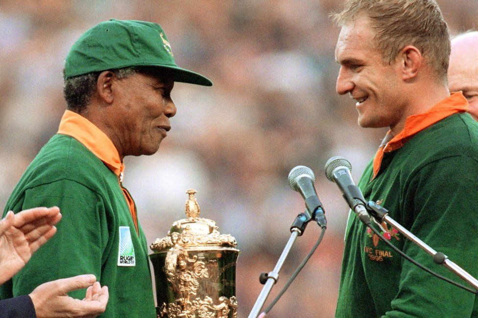 South Africa's president Nelson Mandela congratulates South Africa's rugby team captain François Pienaar before handing him the William Webb trophy after his team's victory over New Zealand (15-12) in the final of the Rugby World Cup at Ellis Park in Johannesburg 24 June 1995