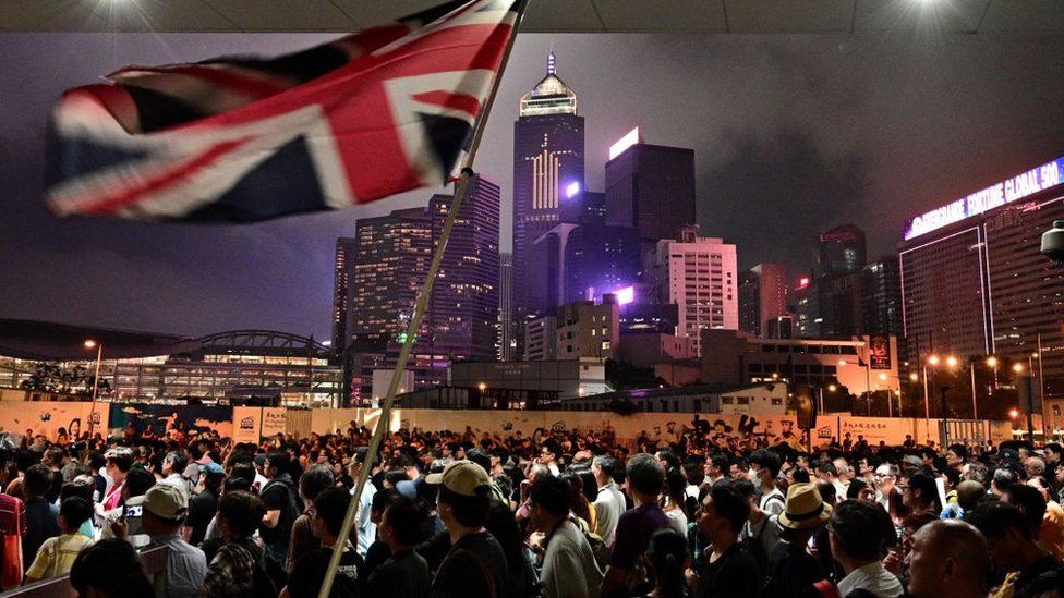 An activist in a large crowd waves a British Union Jack flag during a anti-Chinese government influence protest in central Hong Kong in 2019
