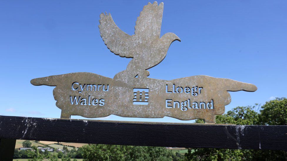 A sign pointing in the direction of Wales and England