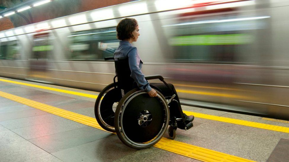Wheelchair user on a platform with a train going past