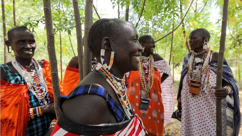 Maasai Kenyan women smiling as they take part in a climate strike. They are wearing their traditional clothing