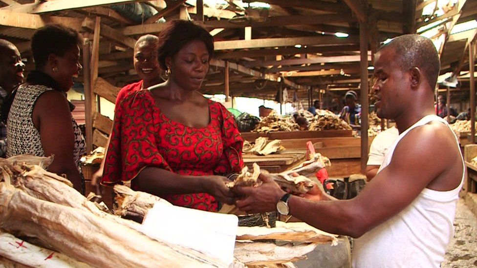 Onyingbo market - a man buys some produce from a woman's wooden stall
