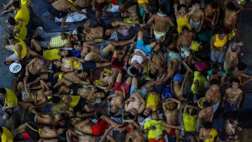 This photo taken on March 27, 2020 shows prison inmates sleeping and gesturing in cramped conditions in the crowded courtyard of the Quezon City jail