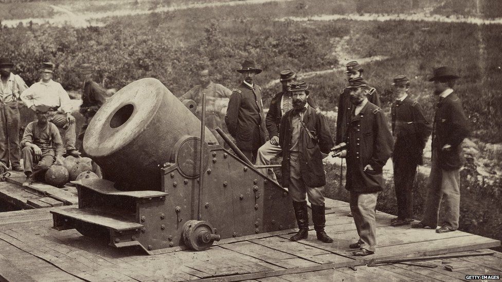 US Civil War soldiers stand near a cannon.