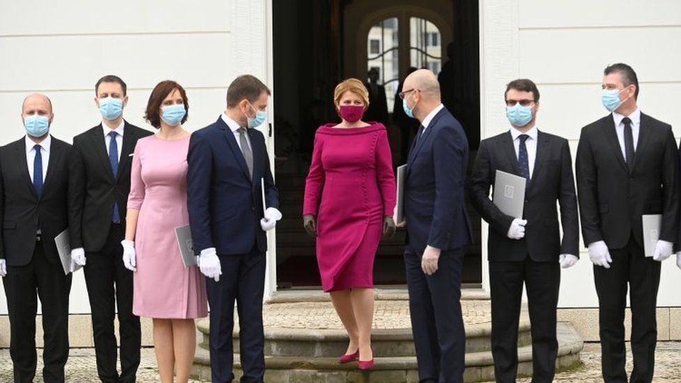 Slovakia's President Zuzana Caputova wears a protective face mask and poses for a photo with new members of the Slovak government