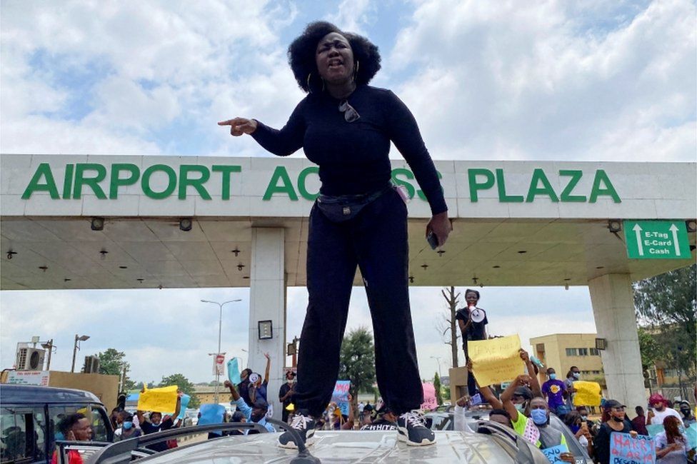 A demonstrator stands atop a vehicle and shouts slogans as others carry banners while blocking a road leading to the airport, during a protest over alleged police brutality, in Lagos, Nigeria October 12, 2020.