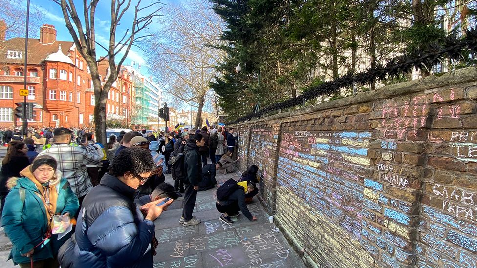 Protesters write chalk messages outside the Russian embassy