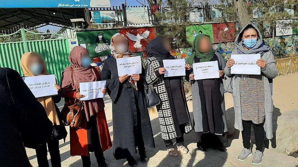 Женщины держат плакаты во время акции протеста на улице