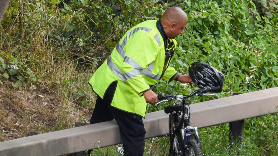 A police officer retrieves a bicycle from the scene