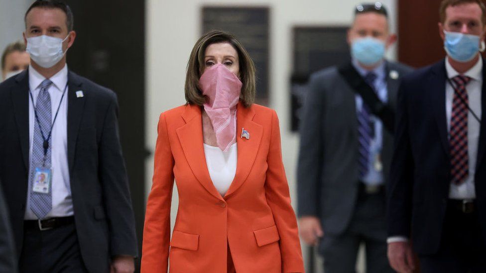 Wearing a scarf over her mouth and nose, Speaker of the House Nancy Pelosi (D-CA) is surrounded by security and staff as she arrives for her weekly news conference during the novel coronavirus pandemic at the US Capitol 24 April, 2020 in Washington, DC