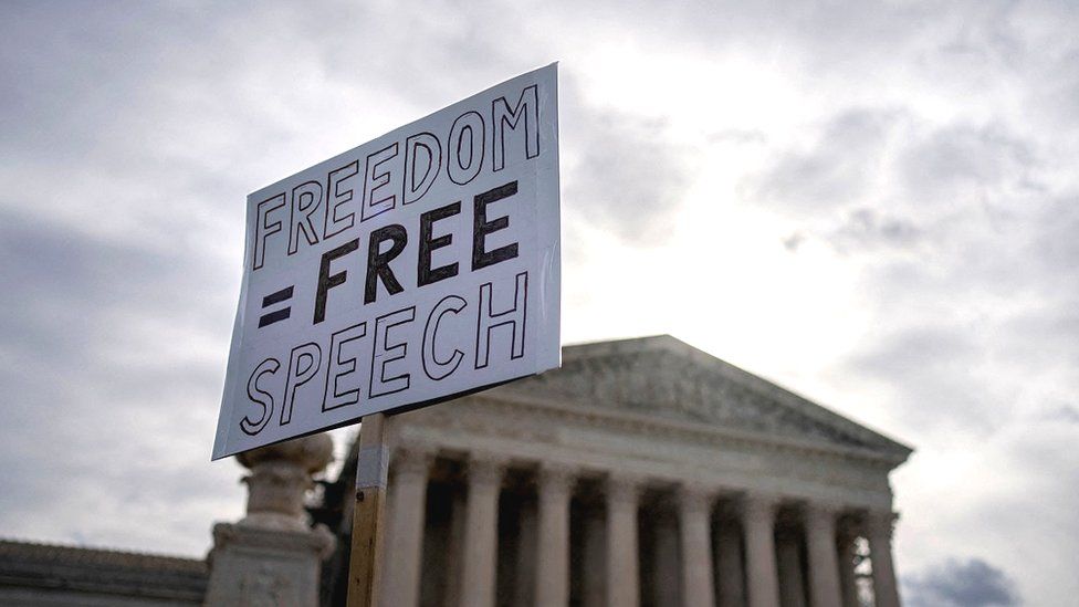 A protester outside the US Supreme Court with a placard reading "Freedom equals free speech"