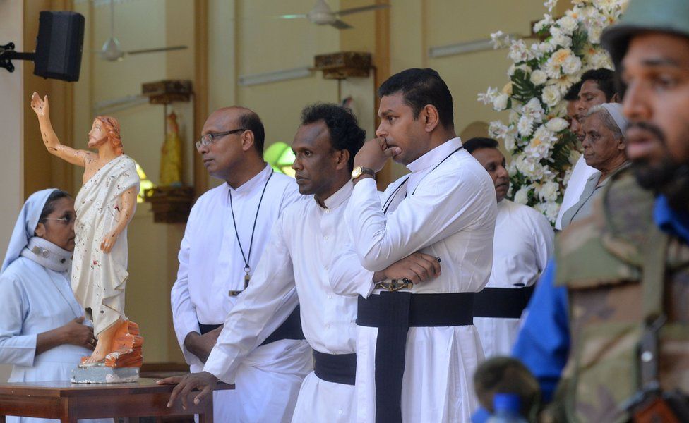 Catholic priests stand inside the church after a bomb blast in Negombo