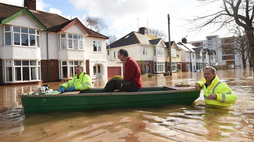 A resident is rescued from a home in a boat by the emergency services amid flooding in Hereford.