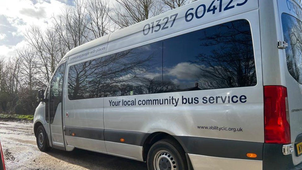A grey Ability minibus with blue "community bus service" lettering