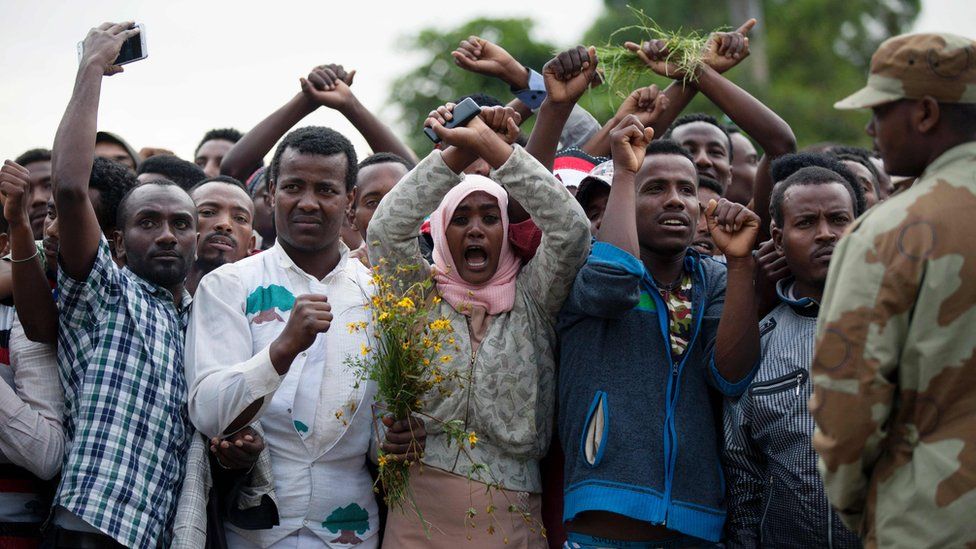 Residents of Bishoftu cross their wrists above their heads as a symbol for the Oromo anti-government protesting movement during the Oromo new year holiday Irreechaa in Bishoftu on October 2, 2016 shows