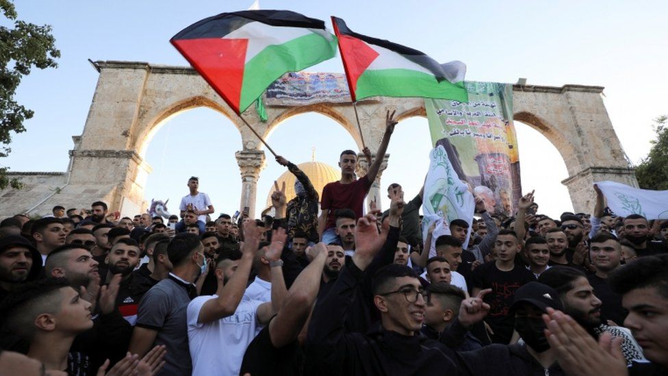 People gathered at the Al-Aqsa mosque waving the Palestinian flag