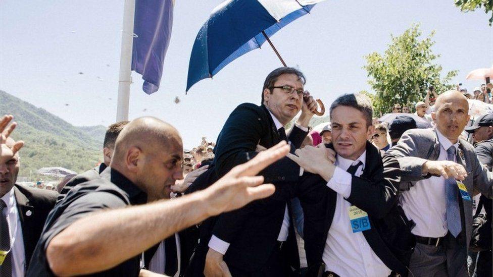 Bodyguards try to protect Serbian Prime Minister Aleksandar Vucic from stones hurled at him by an angry crowd.
