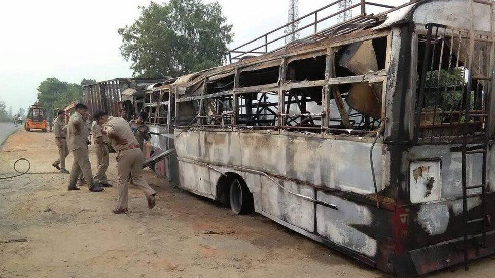 Police officers inspecting the charred bus after the collision