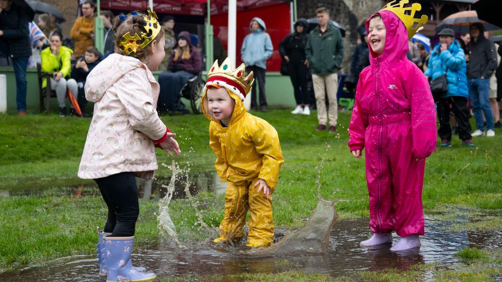 Children wearing crowns play in the puddles at Cardiff Castle