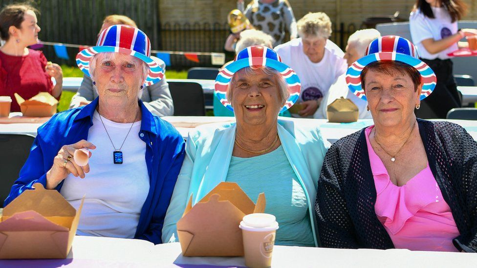 Three women wearing union jack hats at a street party in Lisburn