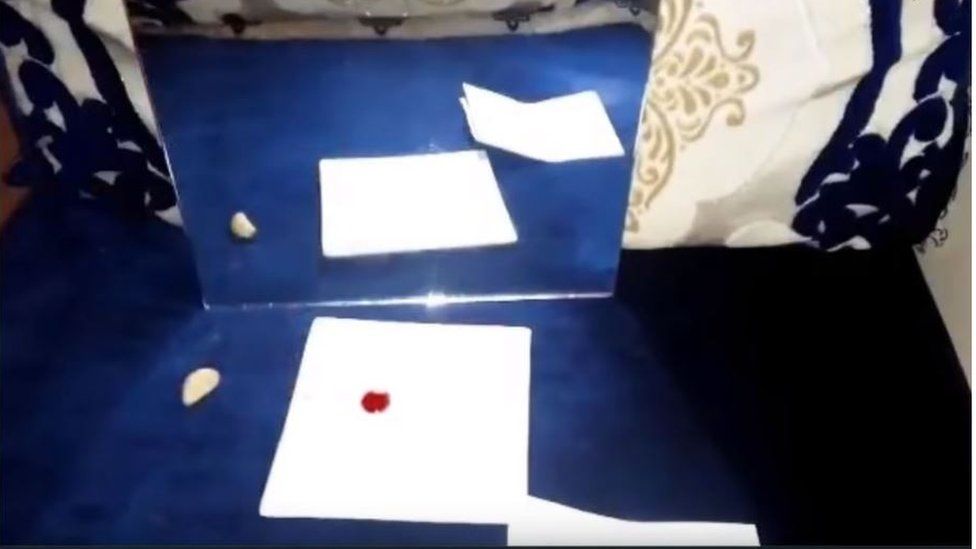 Still from a YouTube which shows an optical illusion - a blob of "red mercury" supposedly not being reflected in a mirror.