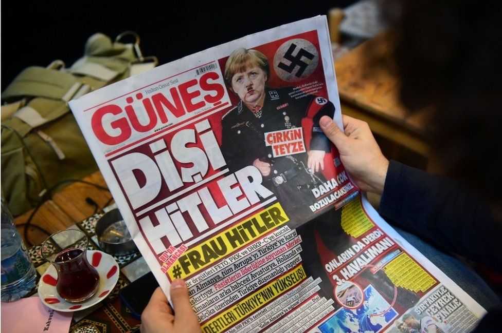 A man reads an issue of Gunes, a Turkish pro-government daily newspaper, with German Chancellor Angela Merkel depicted in Nazi uniform
