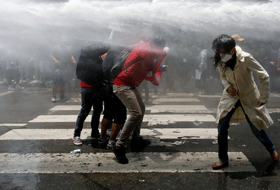 Nepalese youths are sprayed with a water cannon