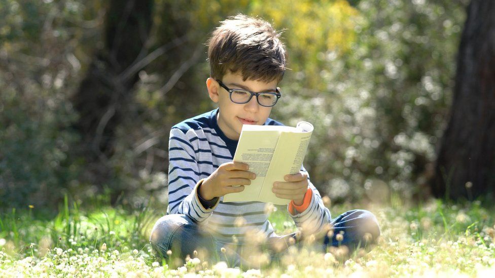 A boy reads outside