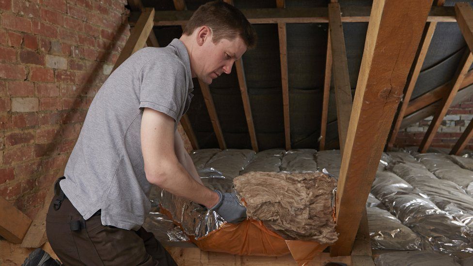 Construction worker installs loft insulation