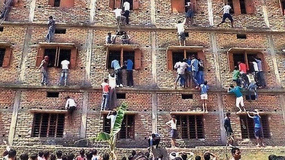 Indians climb the wall of a building to help students appearing in an examination in Hajipur, in the eastern Indian state of Bihar