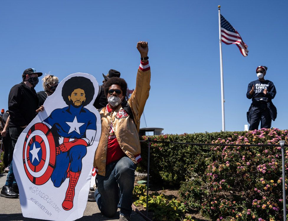 Black Lives Matter protester with photo of Colin Kaepernick in Captain America costume in June 2020
