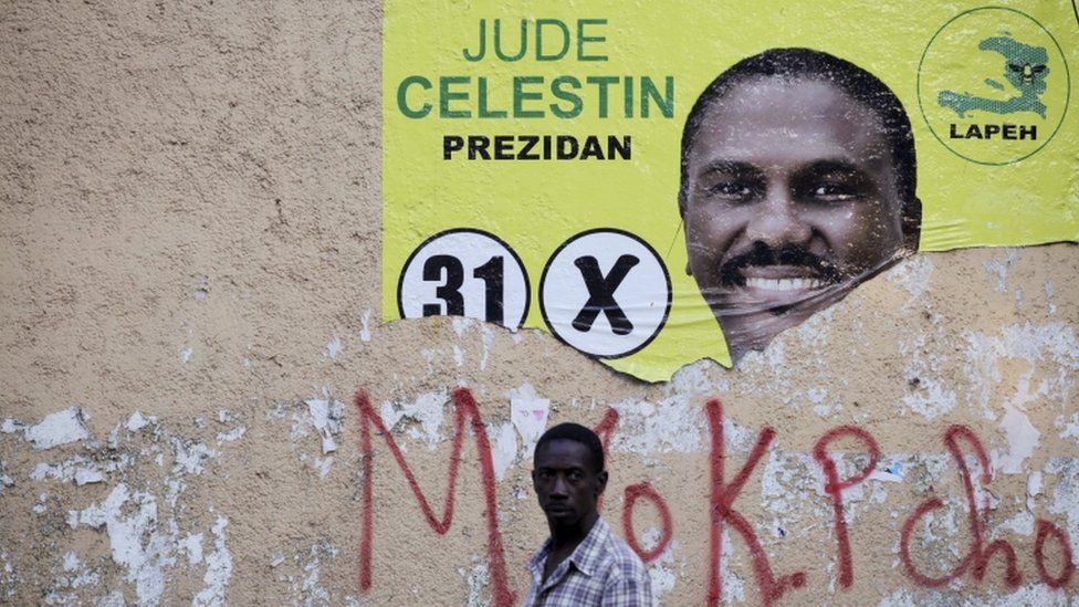 Мужчина идет рядом с разорванным предвыборным плакатом кандидата в президенты Джуда Селестена в Порт-о-Пренсе, Гаити (15 января 2016 г.)