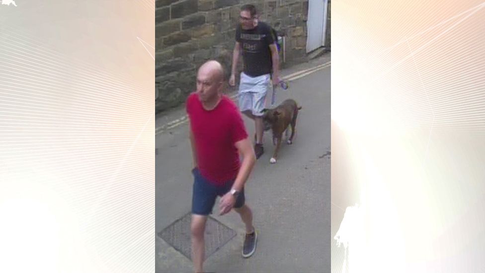 CCTV image of two men walking along a street, one holding a lead with a dog