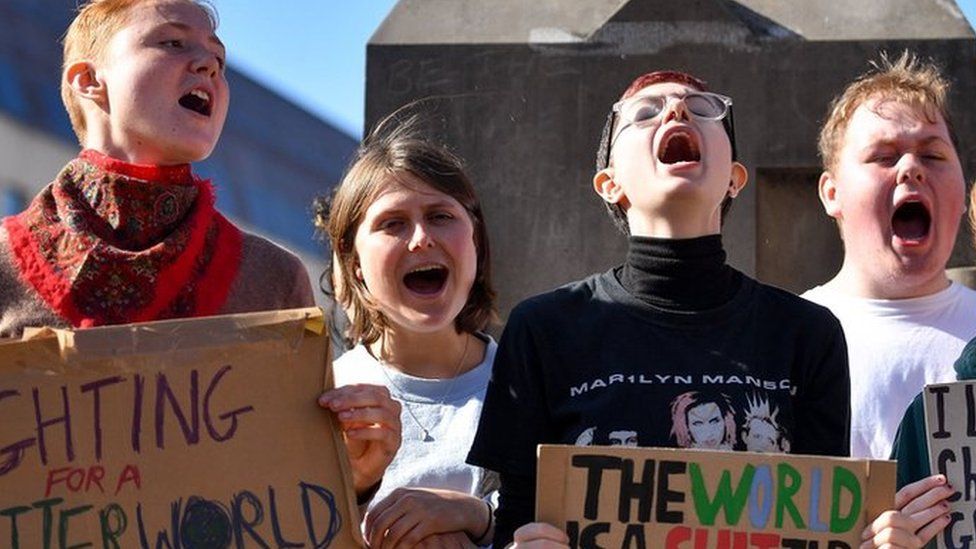 Young "climate strikers" hold up placard in Birmingham city centre
