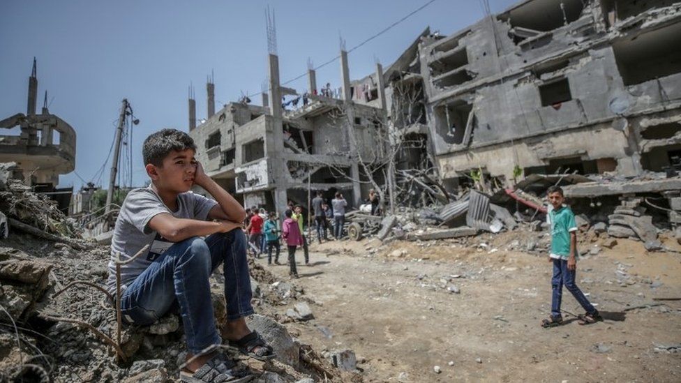A Palestinian boy sits over the rubble of family's destroyed house in Gaza