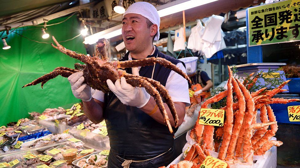 A vendor holds up a crab at the Tsukiji market
