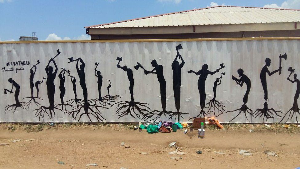 Painted silhouetted figures take axes to their legs, which are drawn with roots of a tree, instead of feed