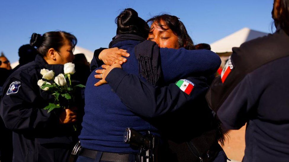 Люди обнимаются, отдавая дань уважения тюремным охранникам, убитым во время нападения на тюрьма в Сьюдад-Хуаресе, Мексика