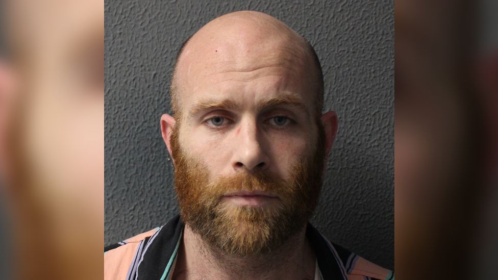 Police custody image of Nathan Arnold, a bald man with a ginger beard