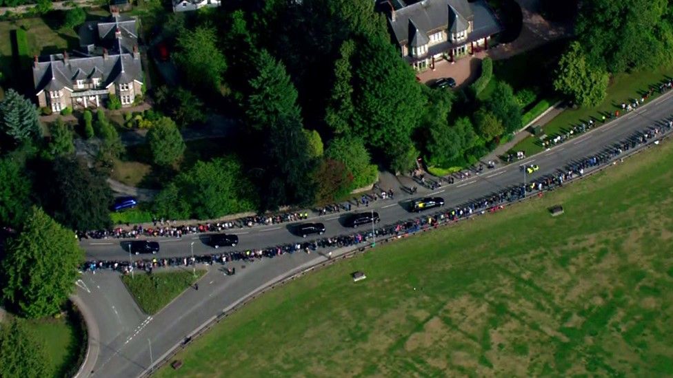 Aerial photo of a line of dark vehicles including the hearse carrying queen's coffin