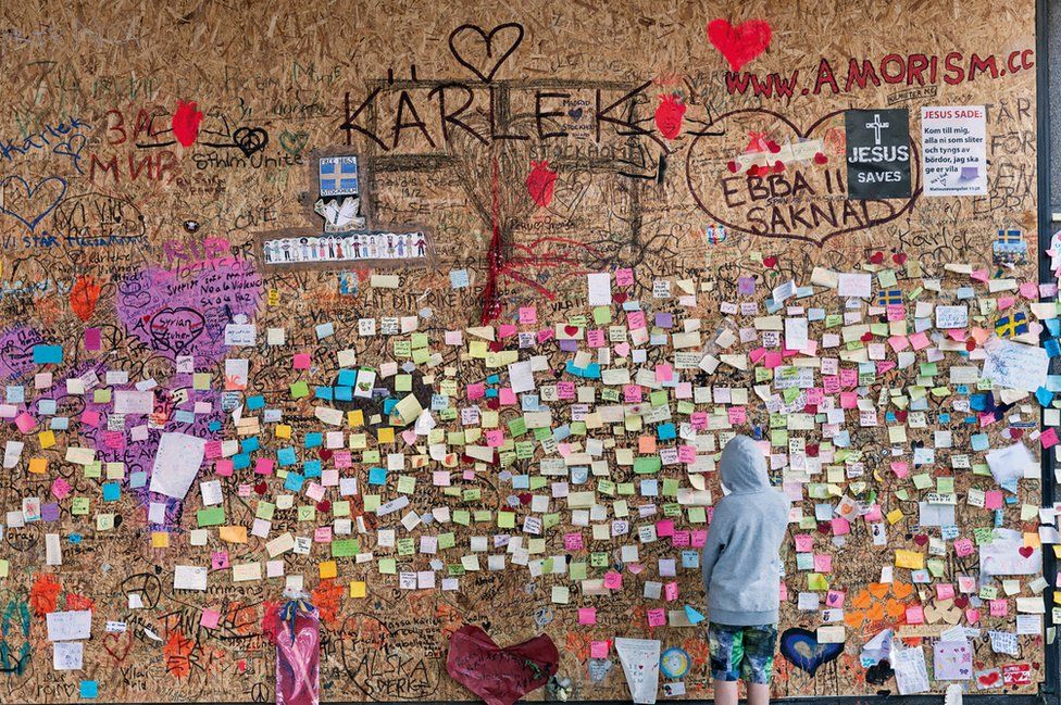 A young boy looks at notes on a wall.