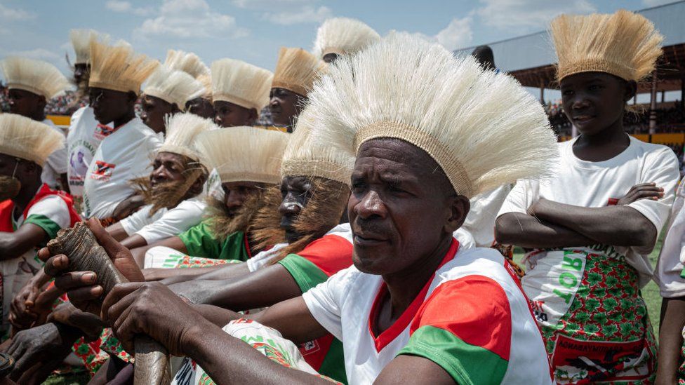 Men sat dressed in traditional Burundian clothing. 26 August.
