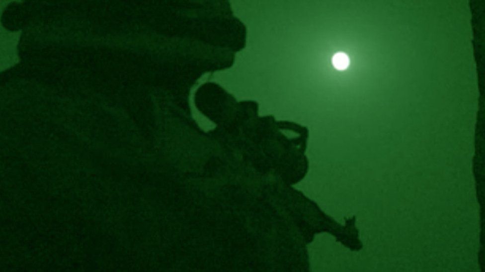 A soldier takes aim at night in Afghanistan.