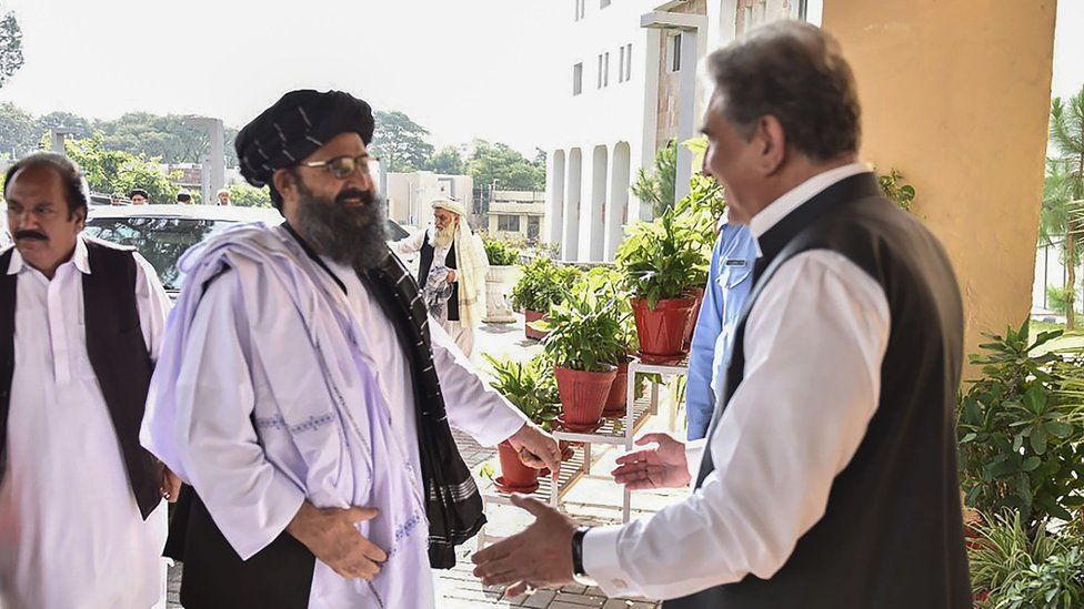 Pakistan's Foreign Minister Shah Mehmood Qureshi greets Taliban co-founder Mullah Baradar upon his arrival with delegation at the Pakistan Foreign Ministry in Islamabad.