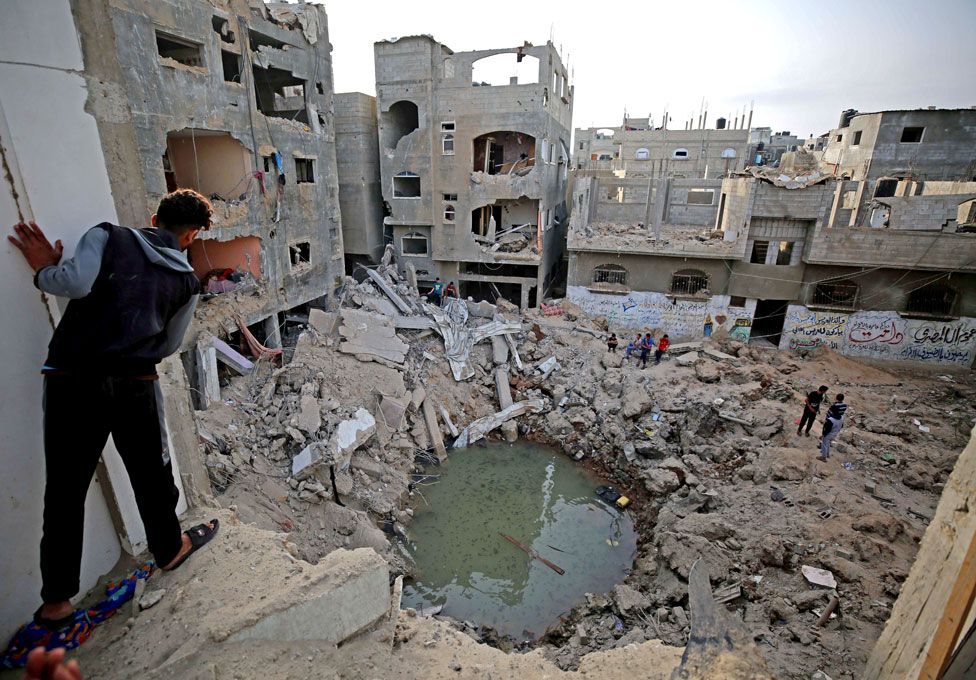 People stand around and look at their bomb-damaged homes in Gaza following a ceasefire with Israel